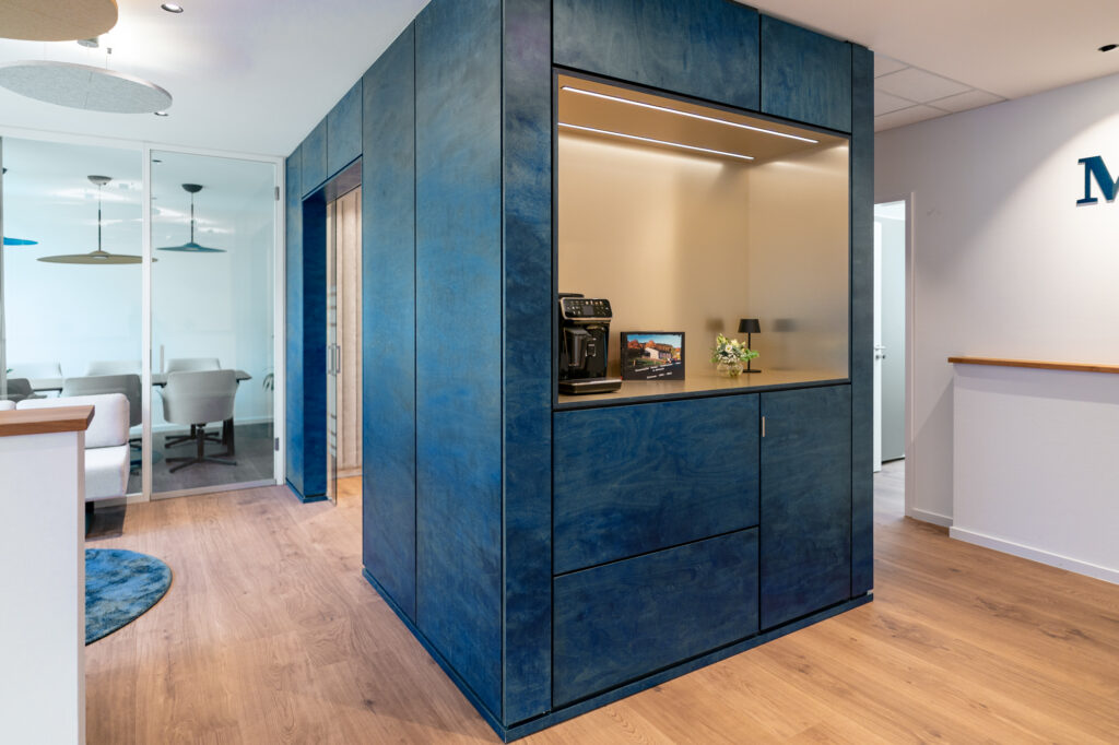 Innenraum mit einem blauen Einbauschrank und offener Nische mit Kaffeemaschine