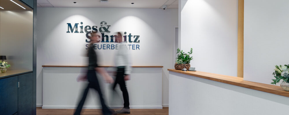Empfangsbereich mit dem Schriftzug “Mies & Schmitz Steuerberater” an der Wand