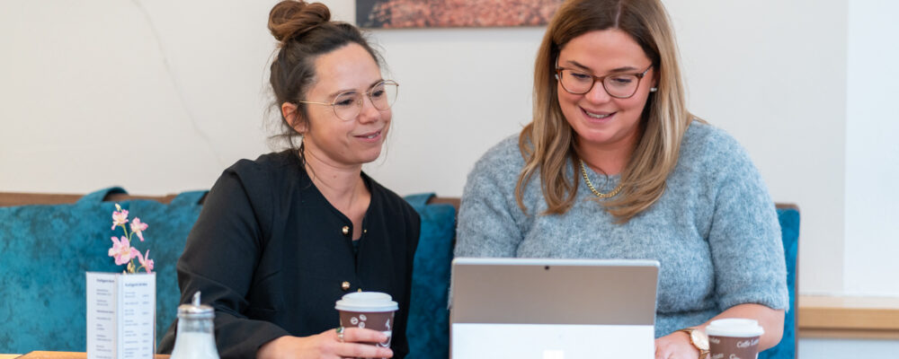 Zwei Frauen arbeiten remote in einem Café